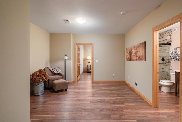 living area with baseboards, visible vents, and wood finished floors