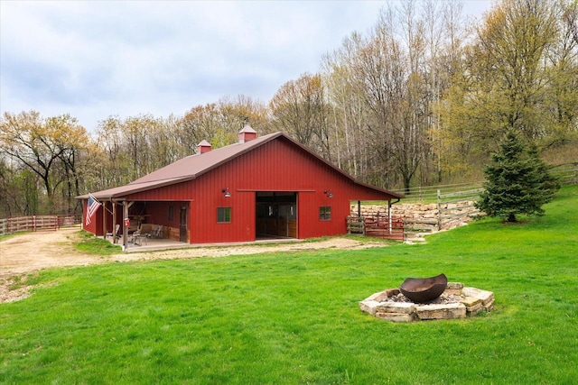 rear view of house with an outbuilding, an exterior structure, a chimney, a lawn, and an outdoor fire pit