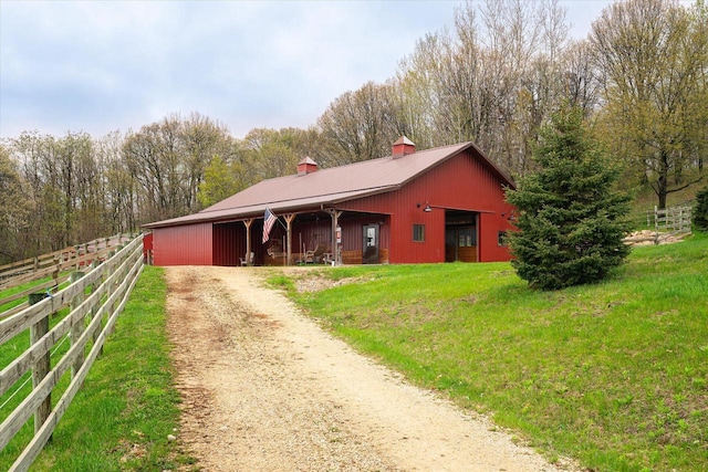 view of front of property with an exterior structure, a chimney, an outbuilding, and driveway