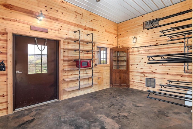 foyer entrance with a wealth of natural light, wooden walls, and concrete floors