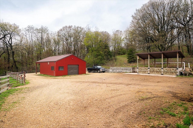 view of yard with an outdoor structure, a garage, fence, and driveway