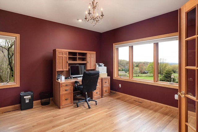 home office with light wood finished floors, a chandelier, and baseboards