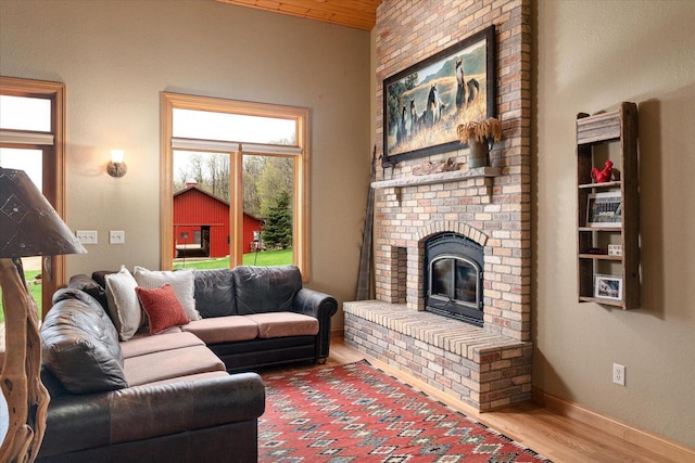 living area with wood finished floors, baseboards, and a brick fireplace