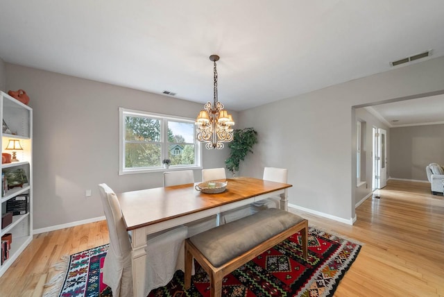 dining area featuring a chandelier, visible vents, light wood finished floors, and baseboards