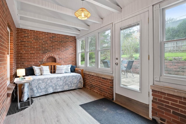 bedroom with brick wall, beam ceiling, multiple windows, and access to exterior
