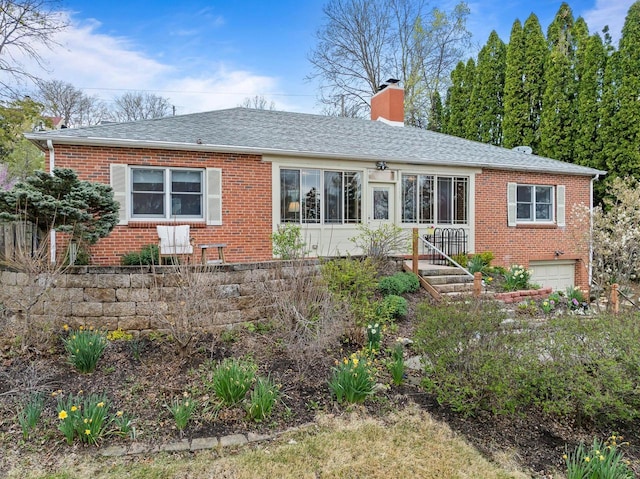 view of front of property with roof with shingles, an attached garage, a chimney, and brick siding