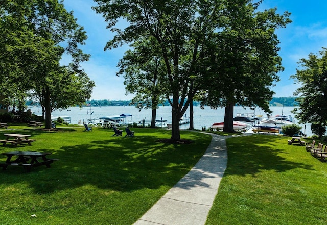 view of home's community with a water view and a lawn