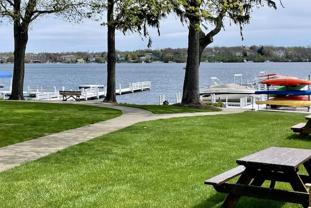 view of dock with a yard, a water view, and boat lift