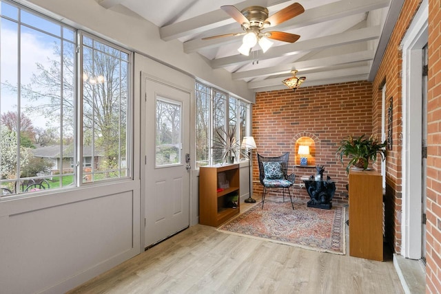 interior space with beam ceiling, wood finished floors, ceiling fan, and brick wall