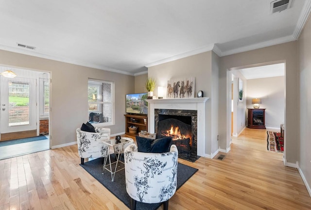 living room featuring light wood-type flooring, visible vents, baseboards, and a premium fireplace