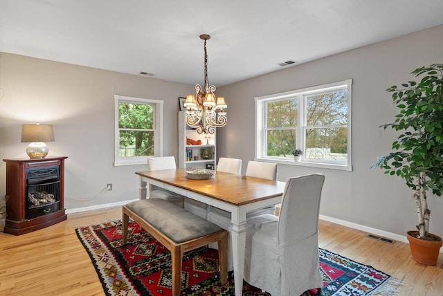 dining area with a notable chandelier, light wood finished floors, and visible vents