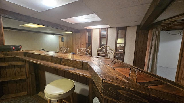 bar with bar, a drop ceiling, and wood walls
