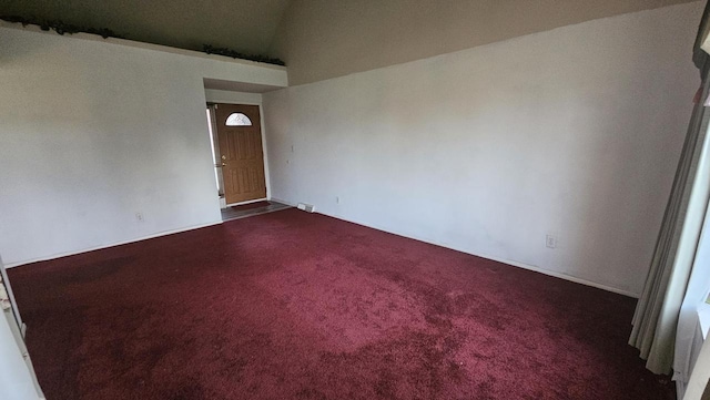 unfurnished room featuring vaulted ceiling and dark carpet