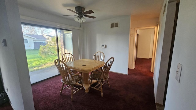 dining space featuring ceiling fan, dark colored carpet, and visible vents