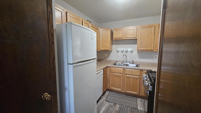 kitchen with light brown cabinets, white appliances, a sink, wood finished floors, and light countertops