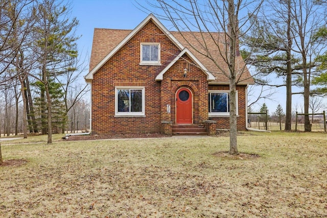6309 12th St, Kenosha, WI 53144 - tudor home featuring a front yard, roof with shingles, brick siding, and entry steps