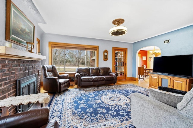 6309 12th St, Kenosha, WI 53144 - living room featuring wood finished floors, a fireplace, a chandelier, arched walkways, and baseboards
