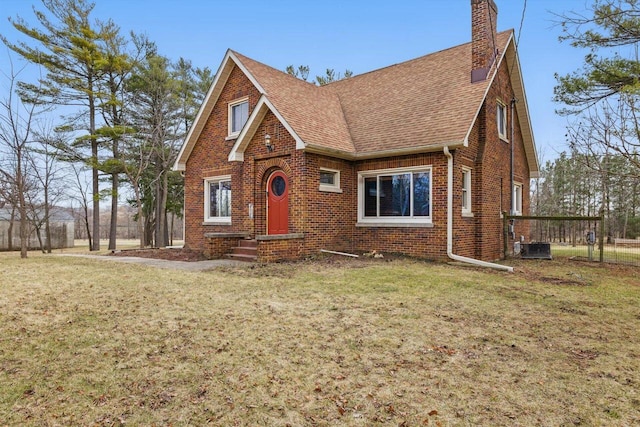 6309 12th St, Kenosha, WI 53144 - tudor home with a chimney, brick siding, roof with shingles, and a front lawn