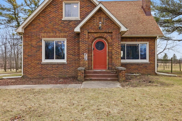6309 12th St, Kenosha, WI 53144 - tudor home with a chimney, a front lawn, brick siding, roof with shingles, and entry steps
