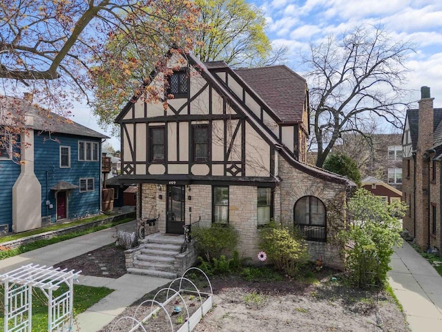 tudor-style house featuring stone siding, stucco siding, and a shingled roof
