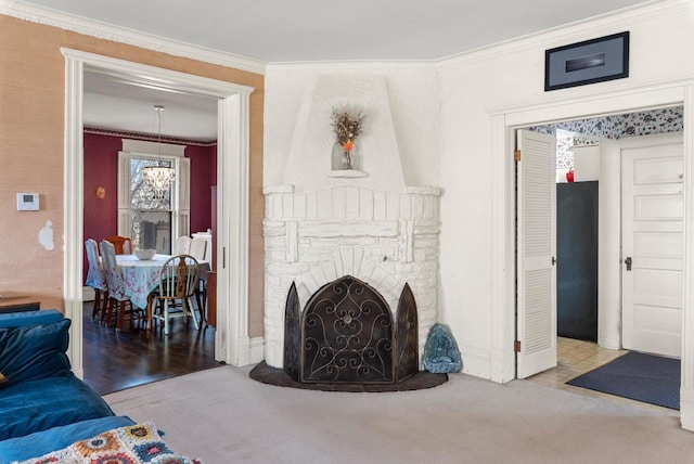 living room with a chandelier, a fireplace, ornamental molding, and carpet floors