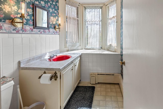 bathroom with wainscoting, tile walls, and plenty of natural light