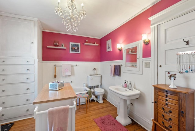 bathroom featuring a tub, toilet, wood finished floors, and a notable chandelier