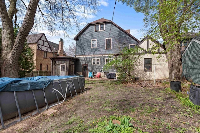 rear view of property with a covered pool