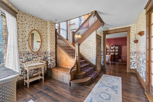 stairway featuring a healthy amount of sunlight, baseboards, wallpapered walls, and wood finished floors