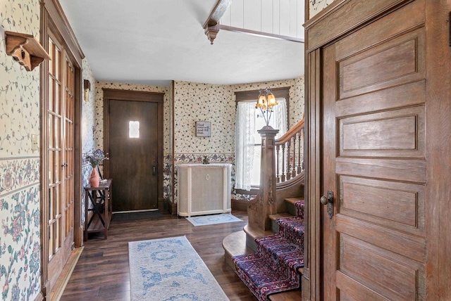 entryway featuring a notable chandelier, stairway, wallpapered walls, and wood finished floors