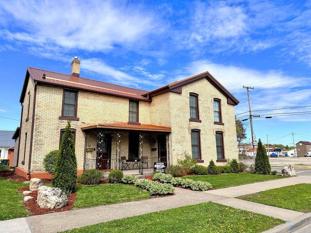 201 S Beaumont Rd, Prairie Du Chien, WI 53821 - view of front of house featuring a chimney, metal roof, a front lawn, a porch, and brick siding