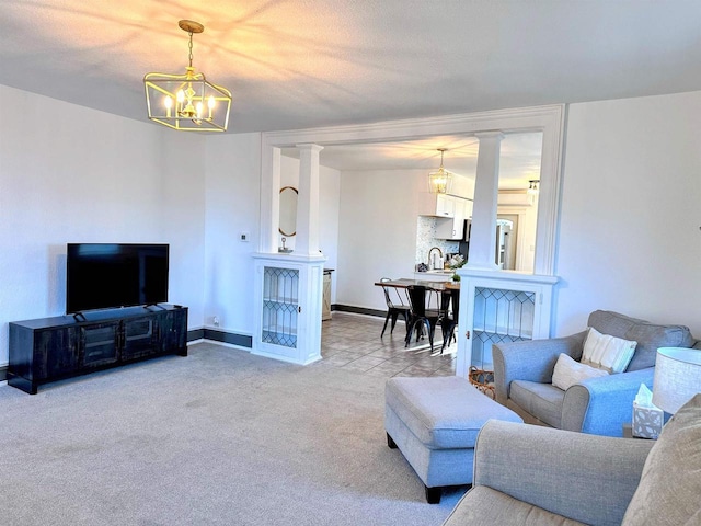 201 S Beaumont Rd, Prairie Du Chien, WI 53821 - carpeted living room with baseboards, ornate columns, a sink, and a notable chandelier