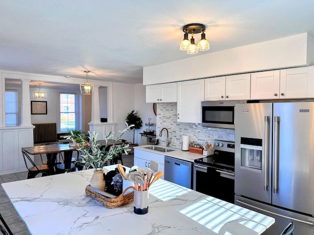 201 S Beaumont Rd, Prairie Du Chien, WI 53821 - kitchen with a sink, ornate columns, white cabinetry, decorative backsplash, and appliances with stainless steel finishes
