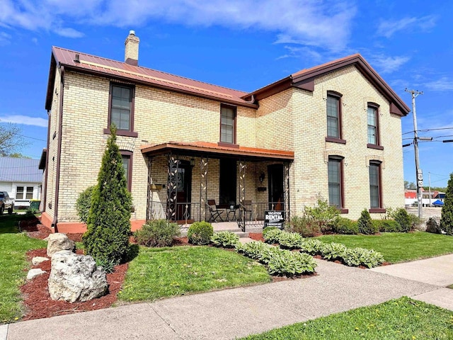 201 S Beaumont Rd, Prairie Du Chien, WI 53821 - view of front of property with covered porch, a chimney, metal roof, a front lawn, and brick siding