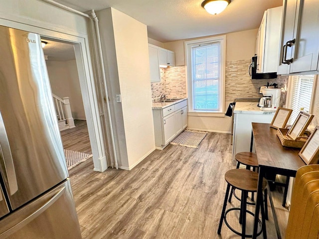 201 S Beaumont Rd, Prairie Du Chien, WI 53821 - kitchen featuring white cabinetry, tasteful backsplash, light wood-type flooring, and a healthy amount of sunlight