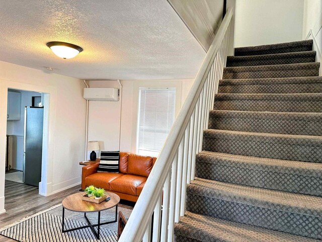 201 S Beaumont Rd, Prairie Du Chien, WI 53821 - stairs with a textured ceiling, wood finished floors, baseboards, and an AC wall unit