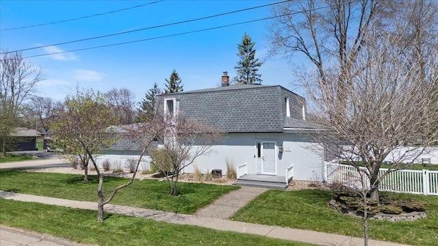 view of front of property with a front lawn, a chimney, a shingled roof, and fence