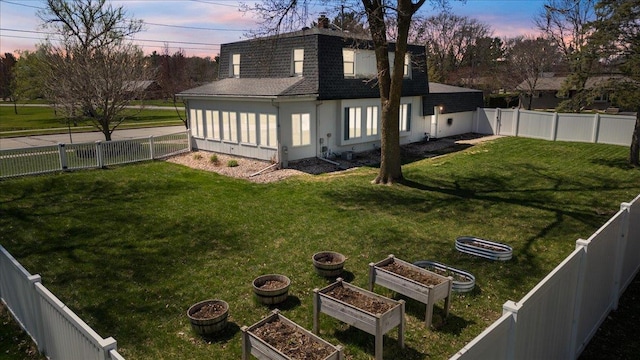 yard at dusk with a garden and a fenced backyard