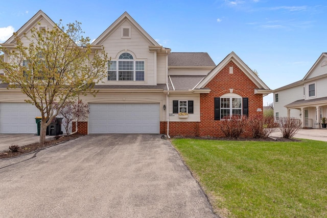 traditional-style house featuring an attached garage, a front lawn, brick siding, and driveway