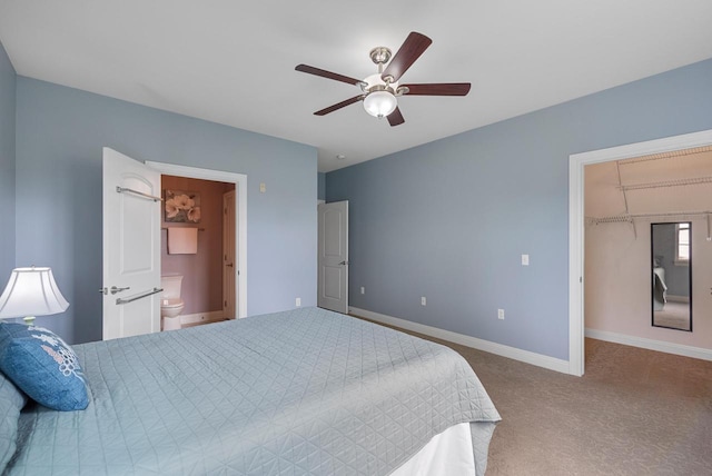 carpeted bedroom featuring a ceiling fan, a closet, baseboards, ensuite bathroom, and a spacious closet