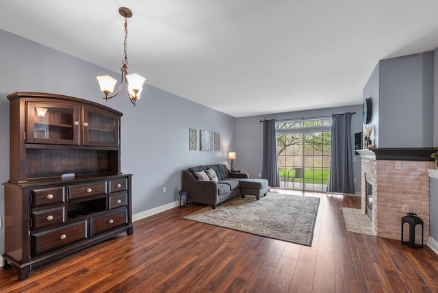 living area with baseboards, dark wood-style flooring, a fireplace, and an inviting chandelier