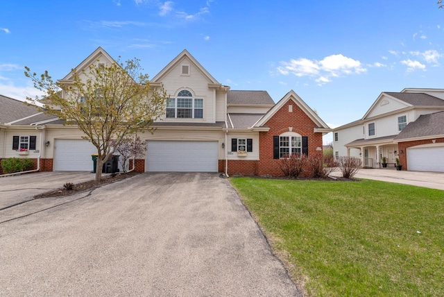 view of front of property with a front lawn, brick siding, an attached garage, and aphalt driveway