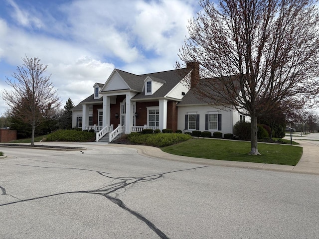 greek revival inspired property with covered porch, a front lawn, and a chimney