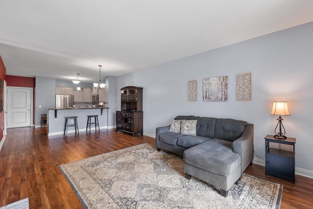 living room with a chandelier, baseboards, and dark wood-style floors