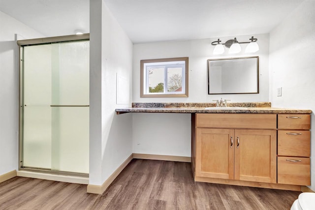 full bathroom featuring a stall shower, vanity, baseboards, and wood finished floors