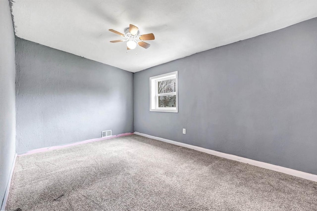 carpeted spare room with baseboards, visible vents, and ceiling fan