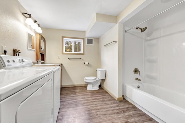 bathroom with toilet, wood finished floors, washing machine and clothes dryer, visible vents, and baseboards