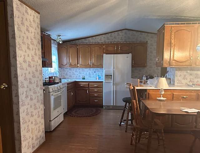 W7730 County Road Z, Pembine, WI 54156 - kitchen featuring wallpapered walls, white appliances, dark wood finished floors, vaulted ceiling, and light countertops