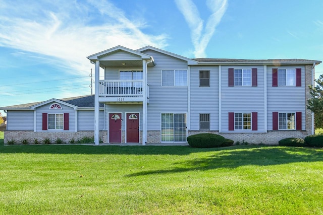 view of front of home featuring a front yard, brick siding, and a balcony