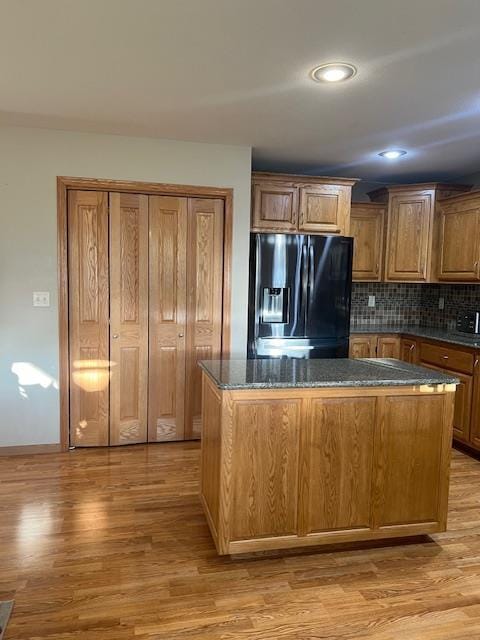 1075 Grant St, Fennimore, WI 53809 - kitchen featuring black fridge, light wood-style floors, decorative backsplash, a kitchen island, and brown cabinets